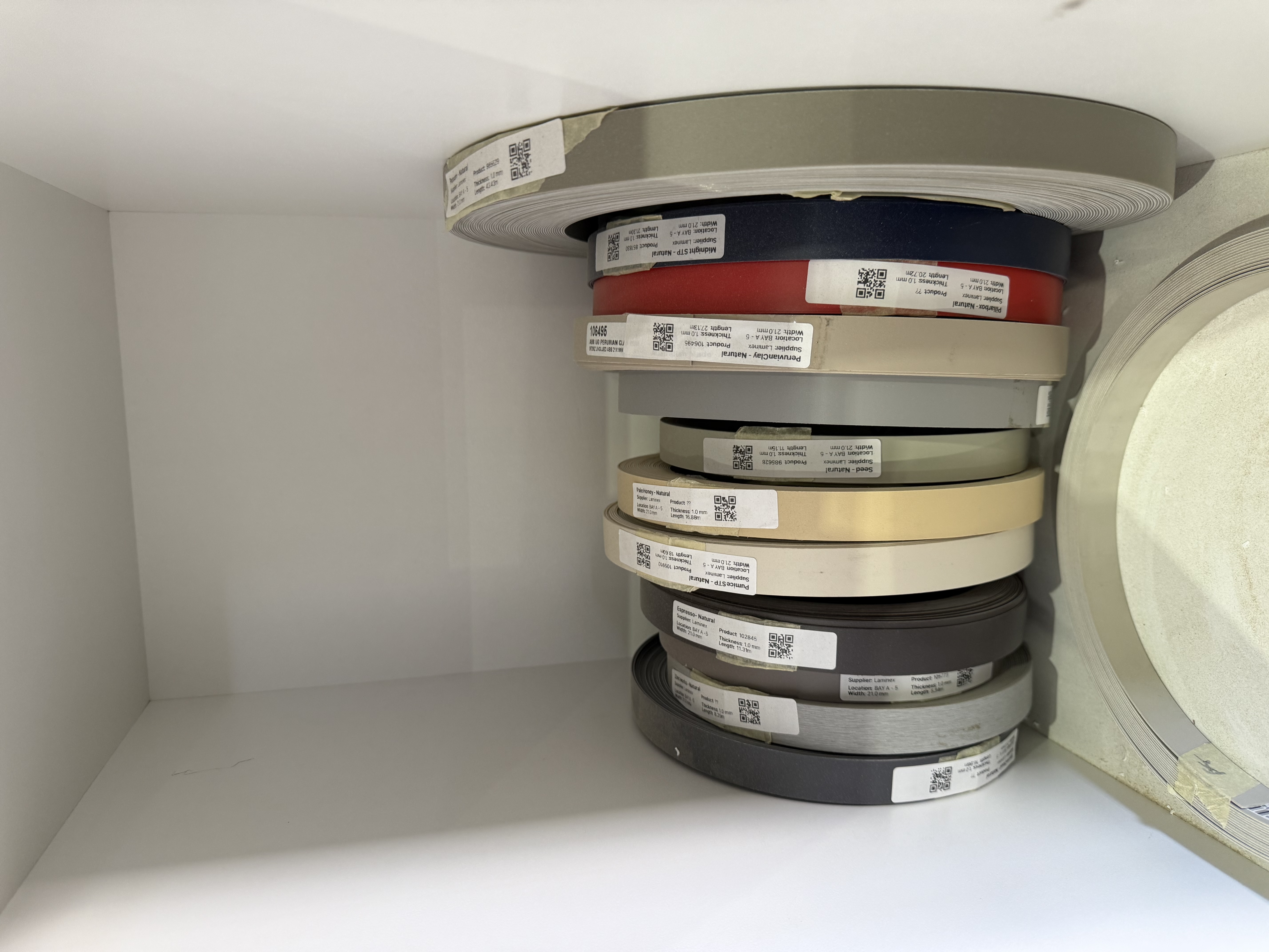 Organized rolls of manufacturing tape labelled with EDGE QR inventory labels